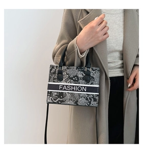 Close-up of black and white embroidery tote bag with FASHION logo and carry handle