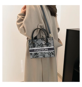 Detail of crossbody bag with floral pattern print and fashion text on beige coat