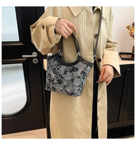 Detail of silk embroidery handbag with white fish pattern and black leather strap