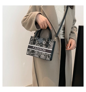Detail of embroidered tote bag featuring floral patterns and fashion text on front