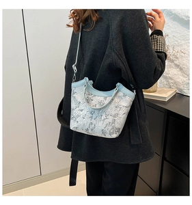 Detail of light blue jacquard bucket bag with silver leaf pattern and leather handle