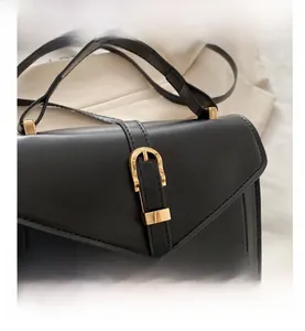 Detailed shot of black flap handbag featuring golden horseshoe buckle and neat stitching