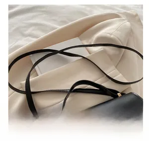 Detail of adjustable strap and golden metal buckle on black leather crossbody bag