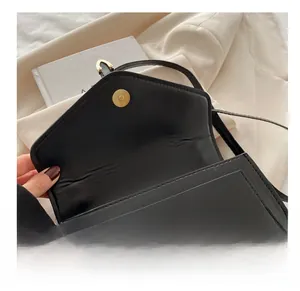 Close-up of the black leather crossbody bag featuring a golden magnetic snap closure