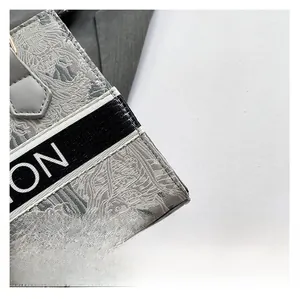 Close-up of grey floral embroidery and branded webbing on canvas tote bag