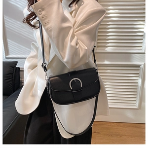 Detail of black saddle bag with silver metallic buckle on a white blazer outfit