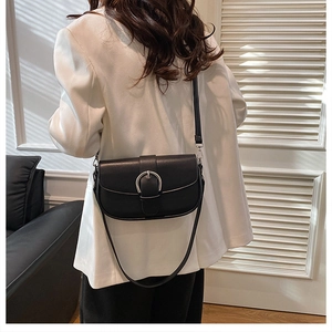 Detail of a matte black saddle bag with silver horseshoe buckle on a shoulder strap