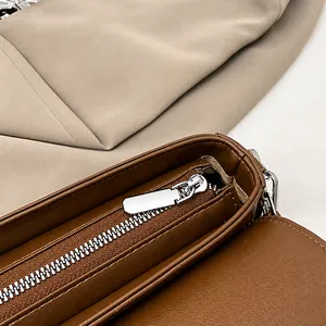 Macro view of the silver metal zipper and brown leather texture on the saddle bag