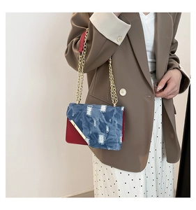 Detail of vintage patchwork crossbody bag with blue denim flap and red leather contrast