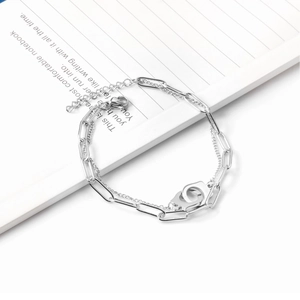 Silver double-layer paperclip chain bracelet with interlocking handcuff pendants