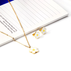 Détails de l'ensemble collier pendentif et boucles d'oreilles marguerite sur un carnet
