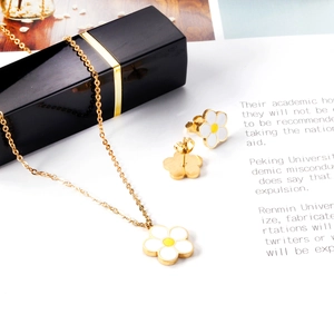 Détail du collier pendentif marguerite dorée et des boucles d'oreilles clous assorties