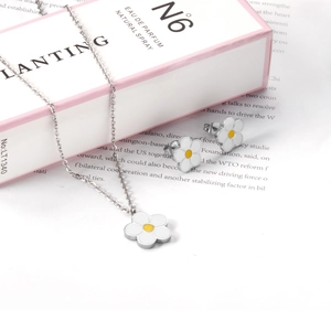 Détail d'un ensemble de bijoux marguerite avec collier fleurs blanches et clous d'oreilles