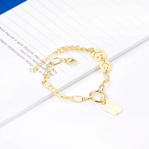Detailed shot of double-strand gold chain bracelet featuring smiley face and Good Luck charms