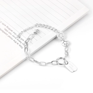 Detail view of silver stainless steel chain bracelet with smile face and Good Luck charms