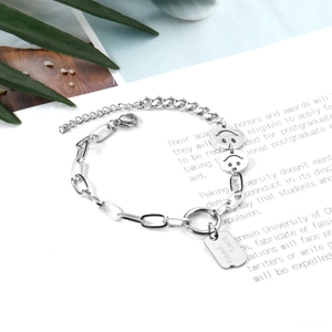 Detail of silver stainless steel mixed chain bracelet with smiley charms and Good Luck tag