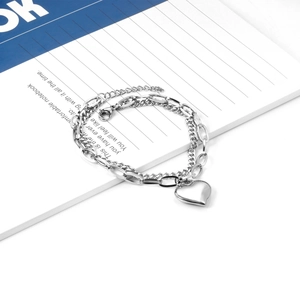 Detail of 18K gold stainless steel double chain bracelet with a polished heart pendant