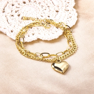 Detail of 18K gold double-layer chain bracelet with polished heart pendant on satin