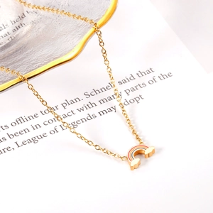 Detailed close-up of rainbow cloud pendant on a golden chain over textured paper