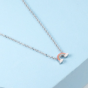 Close-up of rainbow pendant with enamel colors and white clouds on silver chain