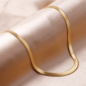 Close-up of gold flat snake chain necklace on beige silk background with soft lighting