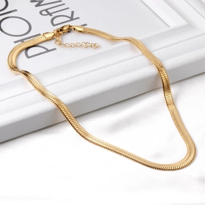 Detail of a polished gold snake chain necklace with lobster clasp on white silk fabric