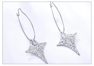 Primer plano de pendientes de estrella plateados con textura martillada y cristal