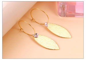 Detalle de pendientes hoja dorada con patrón de margarita y circonita brillante