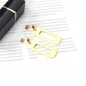 Close-up of golden geometric rectangular hollow drop earrings on an open book page