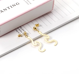 Close-up of golden irregular wave dangle earrings with a polished metallic finish