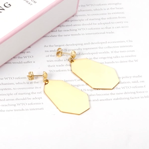 Detailed close-up of golden geometric octagonal drop earrings on an open book background