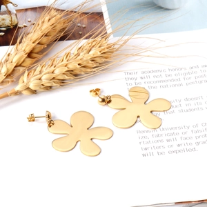 Detailed view of large gold-tone floral earrings with a polished irregular five-petal design