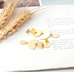 Close-up of gold geometric minimalist dangle earrings placed on an open white magazine