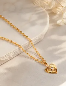 Close-up of golden heart sunburst pendant with center zircon on stainless steel chain