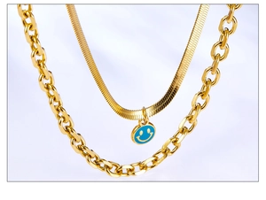 Detail of gold layered chain necklace featuring thick links and blue smiley face pendant