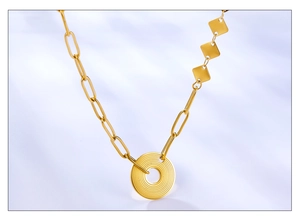 Detail of asymmetric 18K gold necklace with textured circular pendant on silk
