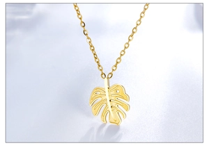 Detailed macro view of gold-plated monstera leaf pendant on a minimalist O-link chain