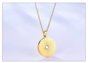 Macro view of golden pendant necklace with radial sunburst pattern and central crystal