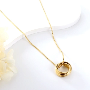 Elegant gold-tone interlocking rings necklace with delicate ball chain on a white display