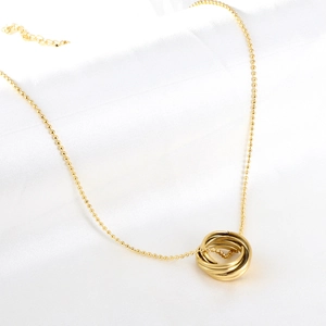 Close-up of golden interlocking rings pendant on a round bead chain necklace