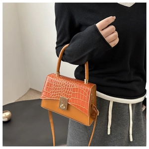 Detail of orange crocodile texture and smooth tan leather with gold clasp closure
