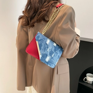 Chic patchwork crossbody bag with red leather and distressed denim featuring a gold chain