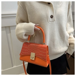 Detail of orange faux crocodile skin handbag with gold metal lock and leather strap