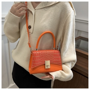 Detail of orange crocodile pattern handbag with gold twist lock and rounded handle