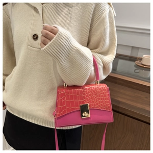 Detail of fuchsia leather handbag with crocodile pattern flap and gold clasp hardware