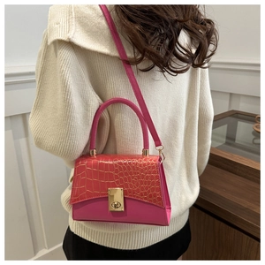 Detail of hot pink crocodile pattern bag with golden metal lock on a female model