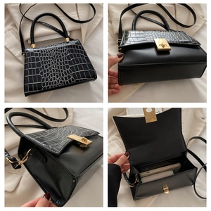 Detail view of black crocodile pattern crossbody bag with golden metal lock and handle