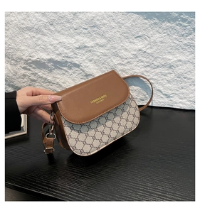 Detail of vintage crossbody saddle bag with brown leather flap and monogram pattern