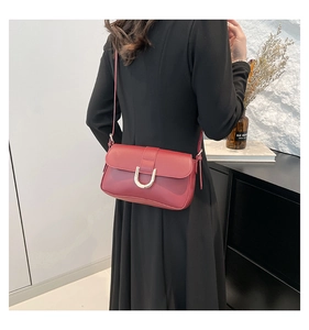 Deep red leather crossbody bag with golden horseshoe buckle shown on model from behind