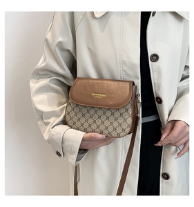 Detail of vintage patterned crossbody bag with brown leather flap and golden lettering